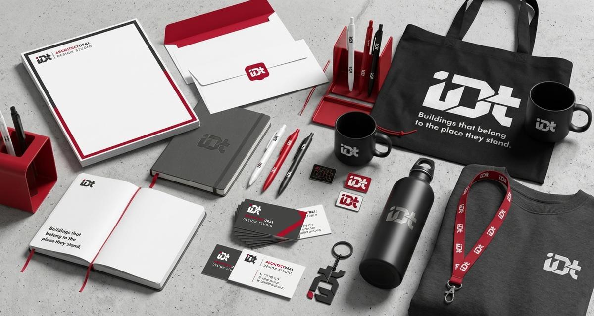 IDT Architectural Design Studio branded stationery, drinkware and tote bags laid out on a light surface